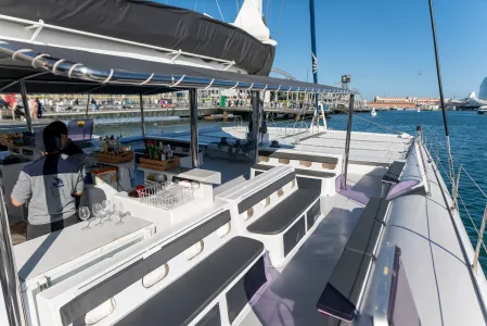Interior of a yacht with seating area and bar overlooking a marina under a clear blue sky.