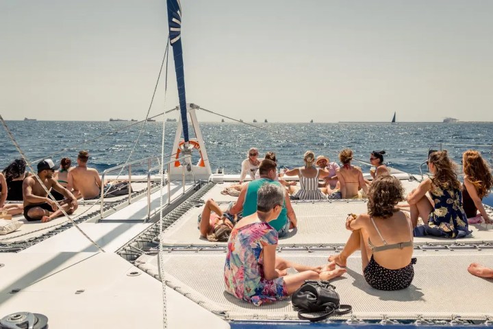 People relaxing on a catamaran at sea under a clear sky.