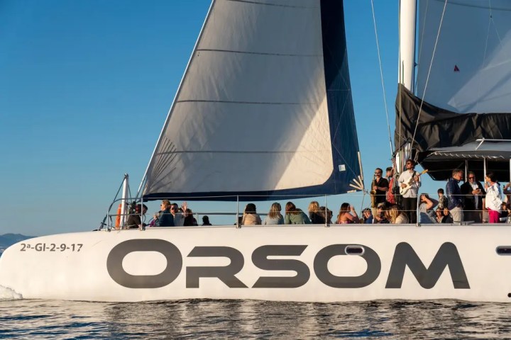 People gathered on a sailing catamaran named ORSOM on calm water.